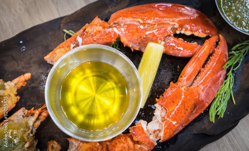 Boiled Lobsters top view. Lobster Cut in half serves. Lobster with Butter sauce. Prepared Lobster on black tray. photo