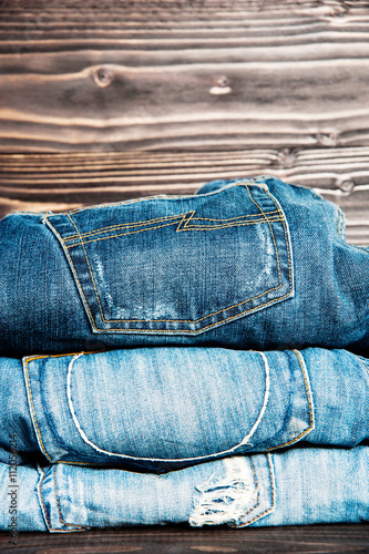 fashionable clothes. pile of jeans on wooden background