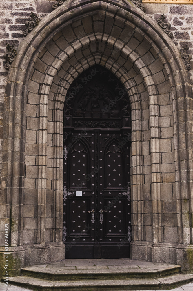 Old castle door oval-shaped among rocky masonry