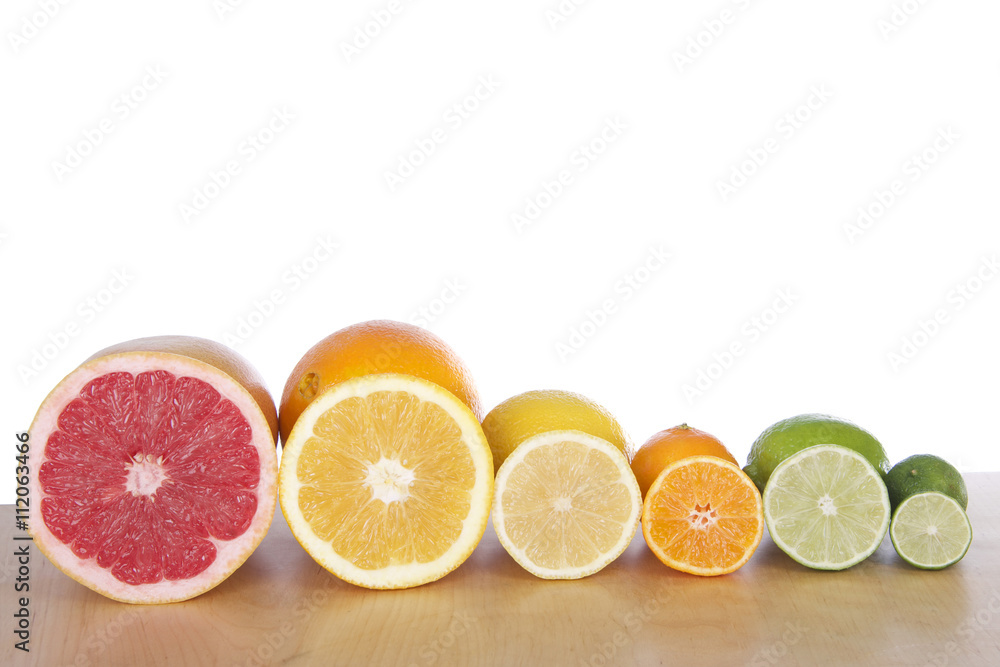 Colorful sliced citrus lined up in rows on a light brown wood table with a white background. Grapefruit, naval orange, lemon, lime, cuties clementine and a key lime Colorful sliced citrus lined up in rows on a light brown wood table with a white background. Grapefruit, naval orange, lemon, lime, cuties clementine and a key lime