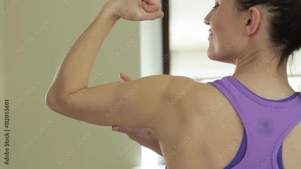 Sporty woman demonstrating biceps, rear view Sporty woman demonstrating biceps, rear view