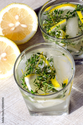 Two glasses of lemonade with thyme, lemon and ice