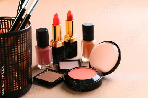 Decorative cosmetics and accessories for makeup on beige background