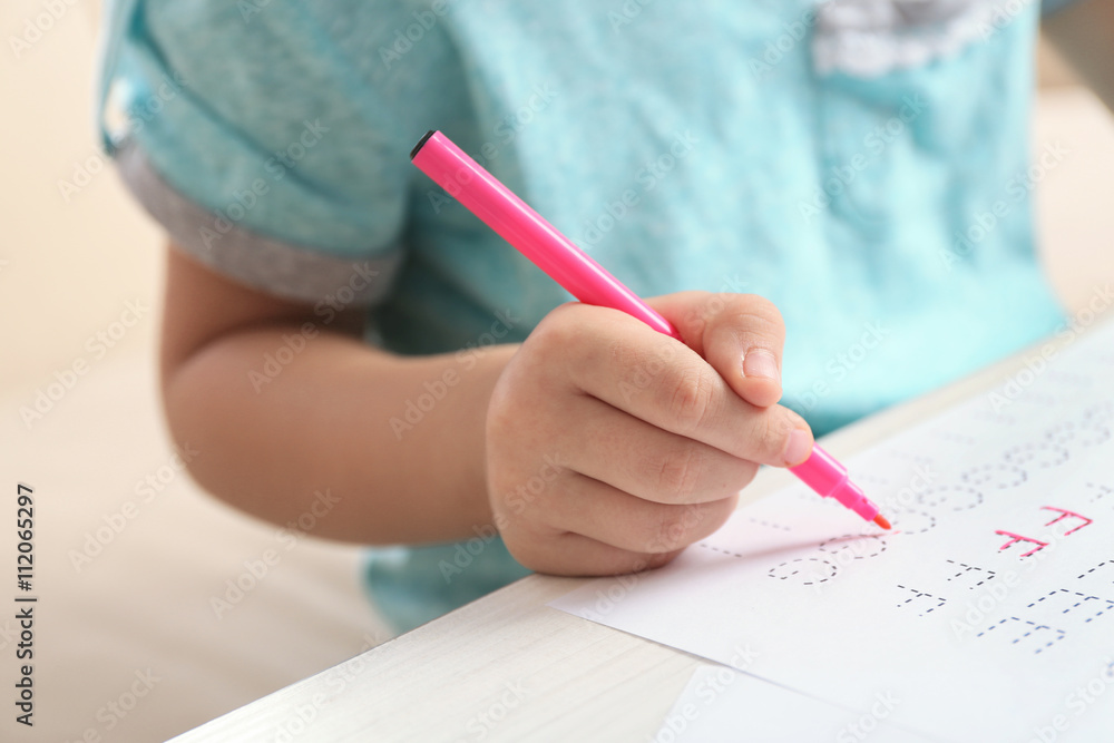 Schoolkid learns to write on sheet of paper, closeup Schoolkid learns to write on sheet of paper, closeup