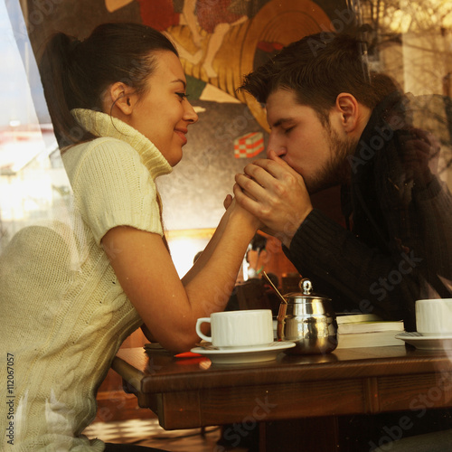 Slika na platnu Young happy couple in cafe, view through a window