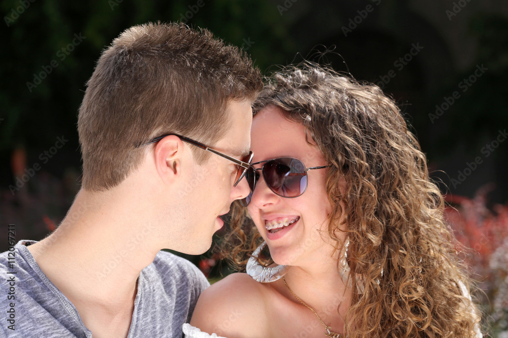 young couple in love with sunglasses, looking each other
