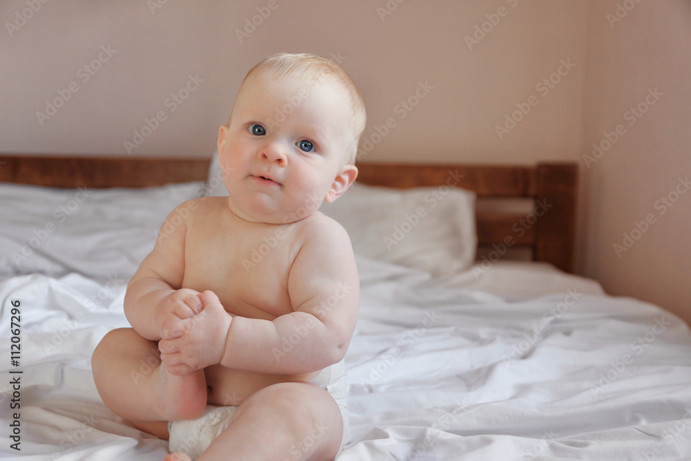 Adorable baby sitting on parents bed, close up Adorable baby sitting on parents bed, close up