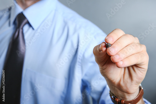 Male hand with pencil on grey background