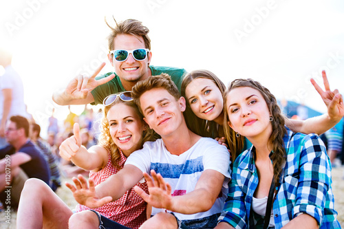 Teenagers at summer music festival, sitting on the ground photo