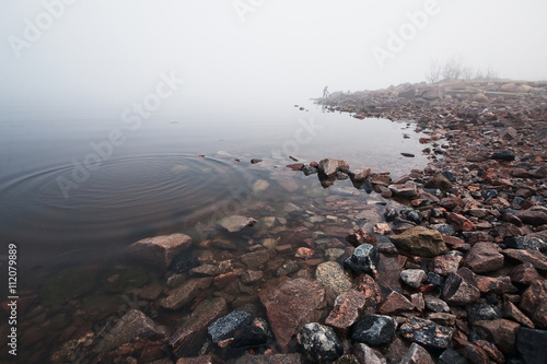 Красивые камни омываются водой залива погруженного в густой туман 
