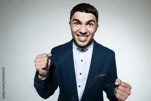 Angry young businessman bares his teeth and clenched his fists  photo