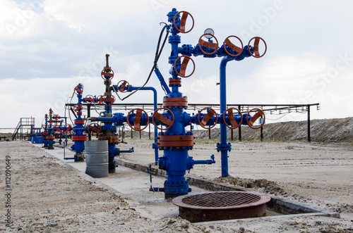 Group of wellheads and pipeline. Oilfield with sand ground. Oil and gas concept.  photo