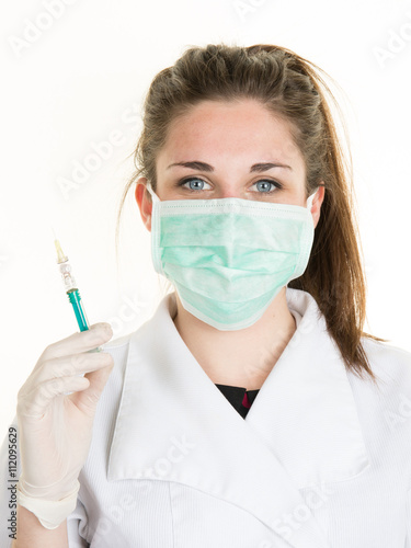 Female doctor in mask and lab coat holding syringe.