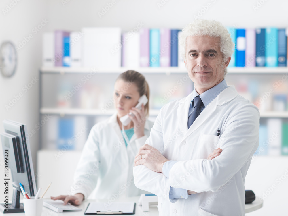A doctor with his assistant in the office A doctor with his assistant in the office