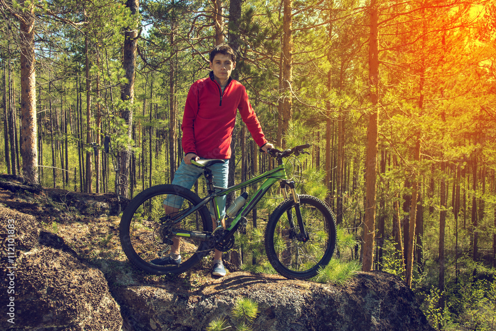 Naklejka premium Man with the bike standing on a rock