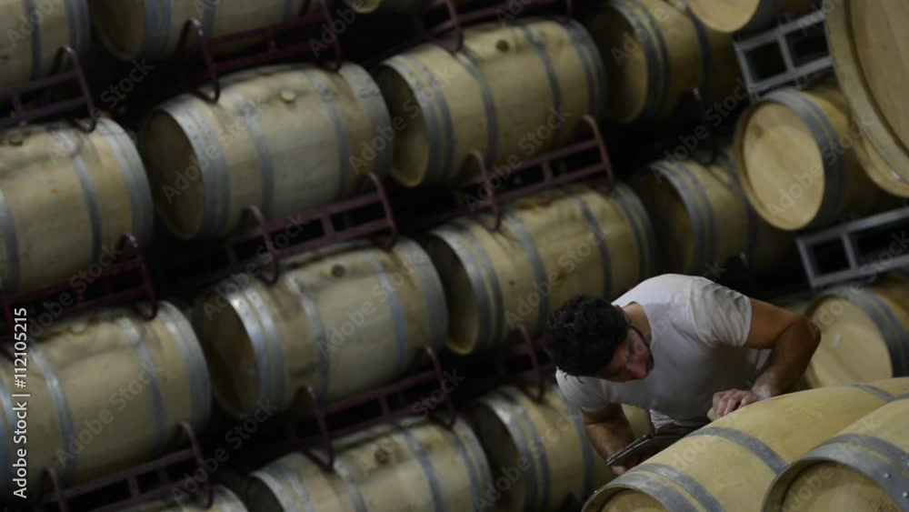 Man smelling wine ntérieur a barrel and noting on a tablet.Wine Barrels in Winery Cellar Bordeaux Wineyard Man smelling wine ntérieur a barrel and noting on a tablet.Wine Barrels in Winery Cellar Bordeaux Wineyard