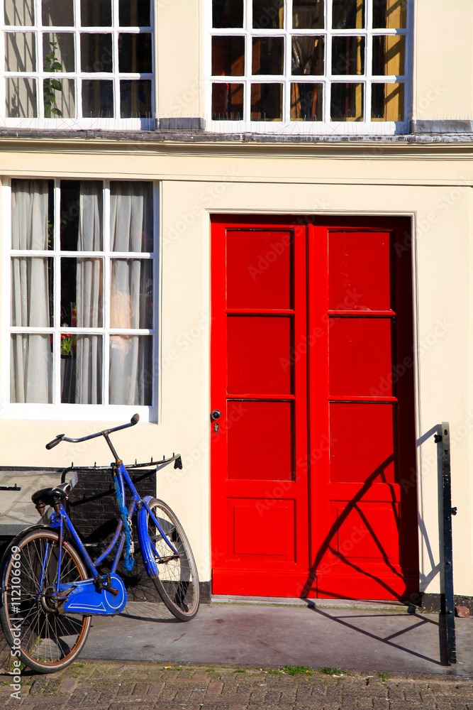Red door and blue bicycle in old european house, Amsterdam.