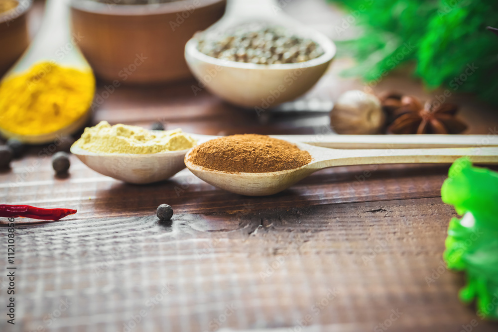 Beautiful colorful spices in wooden spoons and bowls with lettuce, dill and Basil on an old wooden brown table. Free space for your text Beautiful colorful spices in wooden spoons and bowls with lettuce, dill and Basil on an old wooden brown table. Free space for your text