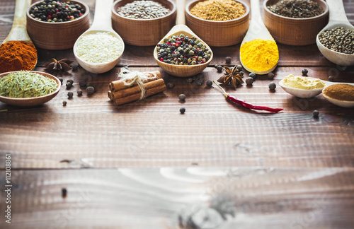 Fototapeta Naklejka Na Ścianę i Meble -  Beautiful colorful spices in wooden spoons on an old wooden brown table. Free space for your text