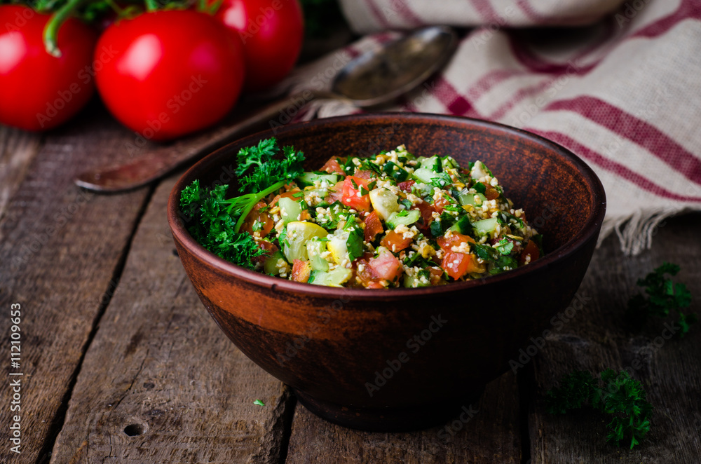 Fresh tabbouleh, a Middle Eastern salad, in clay bowl on wooden background. Selective focus. Toned image Fresh tabbouleh, a Middle Eastern salad, in clay bowl on wooden background. Selective focus. Toned image