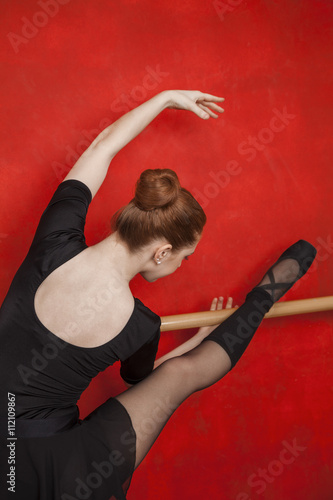 Ballerina Stretching At Barre Against Red Wall