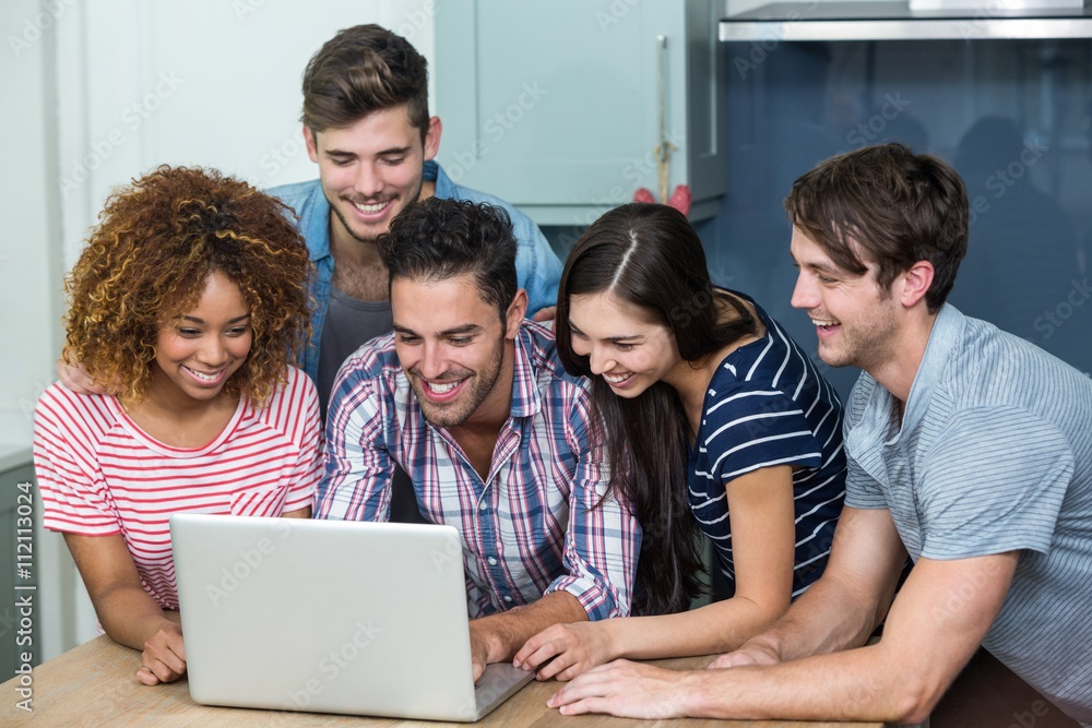 Fototapeta premium Multi-ethnic young friends looking in laptop on table