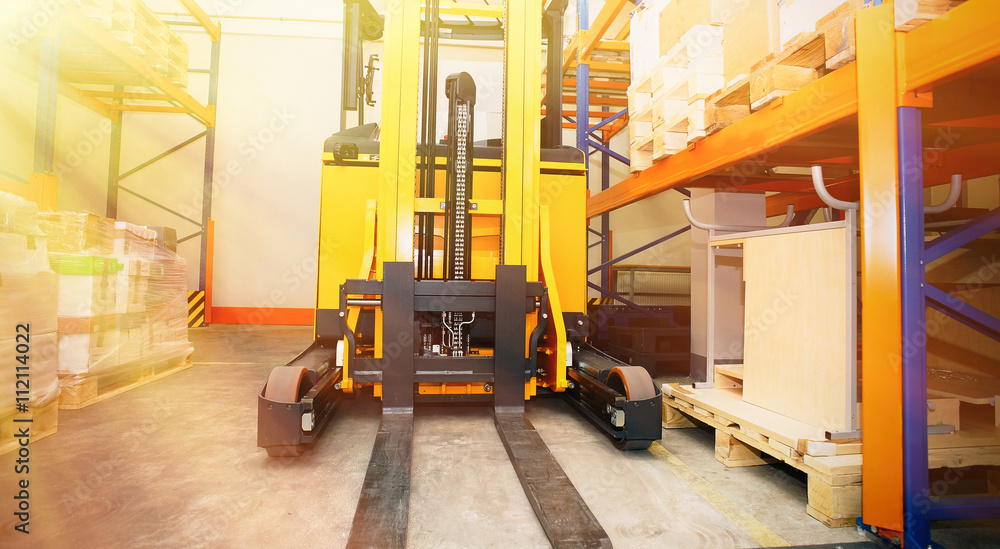 Forklift, shelves and racks with pallets in distribution warehou