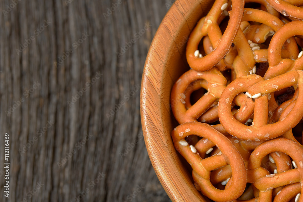 Pretzels baked with sesame seeds in a wooden bowl - top view, rustic view. Pretzels baked with sesame seeds in a wooden bowl - top view, rustic view.