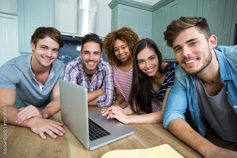 Portrait of young friends smiling while using laptop Portrait of young friends smiling while using laptop