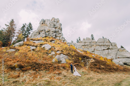 Bild auf Leinwand Newlywed couple on majestic outdoor landscape with massive rocks as backround