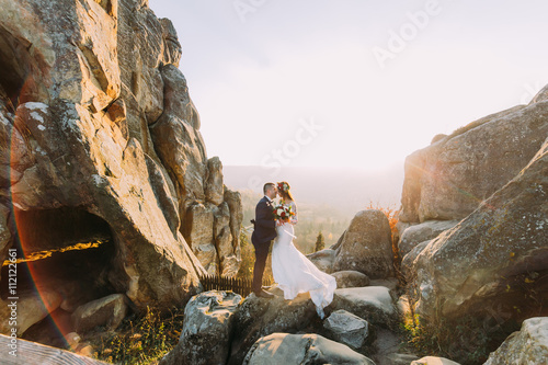 Foto Portrait of romantic newlywed couple in yellow sunset lights on majestic mountai