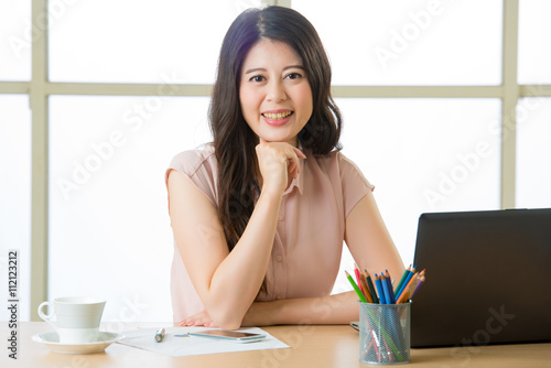 Tableau sur toile Successful Asian female entrepreneur sitting and smiling at desk