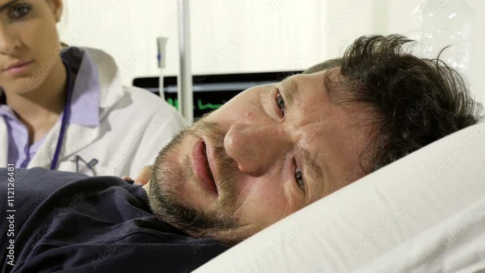 Dolly shot of sick sad man in hospital crying looked by female doctor