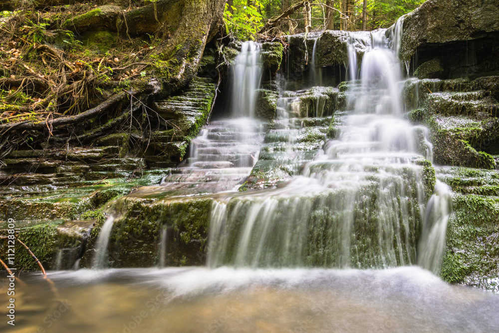 waterfall between mossy rocks. beautiful forest stream waterfall between mossy rocks. beautiful forest stream
