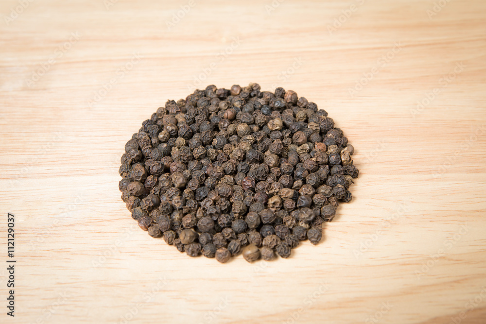 pile of black dried pepper on a wood background pile of black dried pepper on a wood background