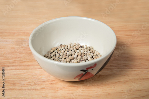 bowl of white dried pepper on a wood background