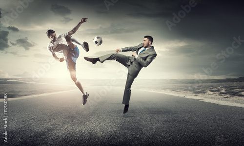 Businessman kicking ball