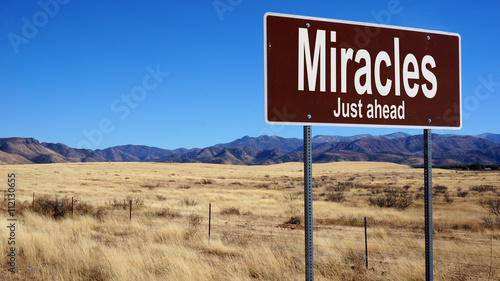 Miracles Just Ahead brown road sign