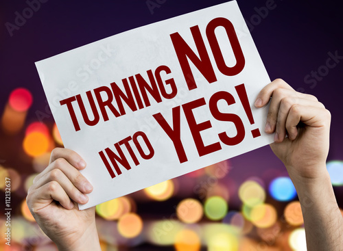 Turning No Into Yes placard with night lights on background photo