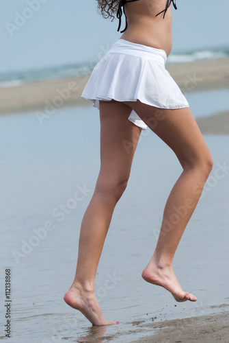 Slim woman walking and plying at sea
