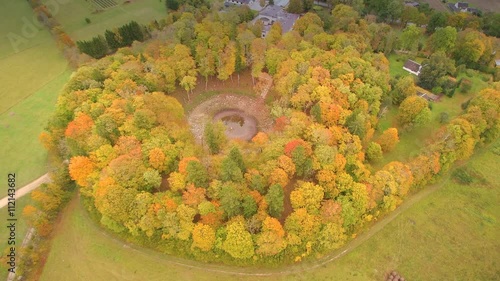 Tall trees surrounding the meteorite crater that is found in the middle of the green fields area in Kaali