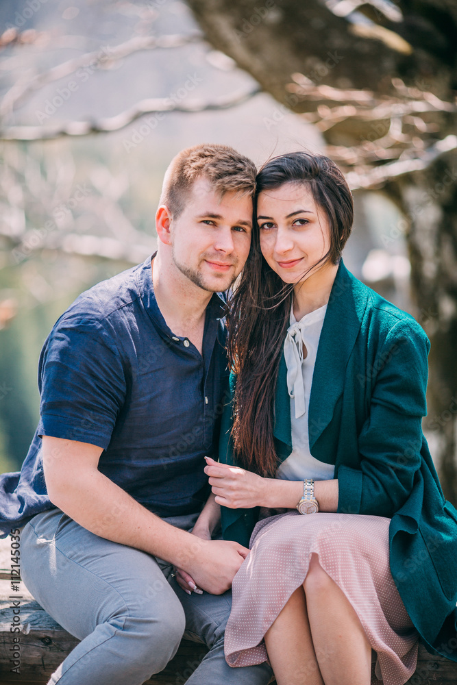 beautiful couple hugging and walking near big near a tree in mountain. Summer day. Woman in dress. Couple with little dog. beautiful couple hugging and walking near big near a tree in mountain. Summer day. Woman in dress. Couple with little dog.