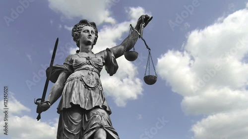 Statue of Lady Justice in front of moving clouds