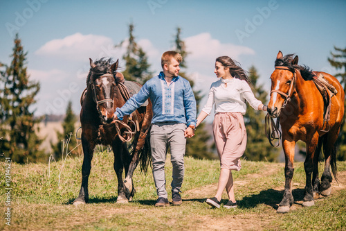 Young couple walking with two horses in the mountains © nataliakabliuk