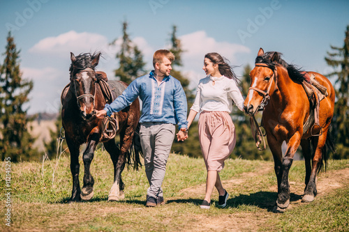 Young couple walking with two horses in the mountains