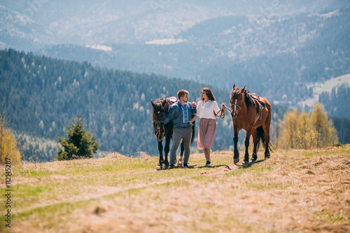 Young couple walking with two horses in the mountains © nataliakabliuk