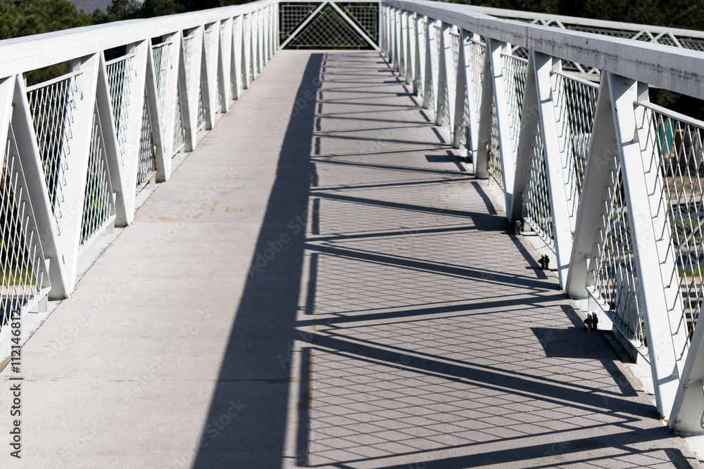 Geometric shadow created by the sunlight on a metal footbridge Geometric shadow created by the sunlight on a metal footbridge