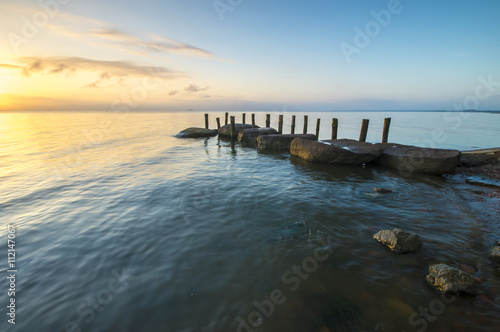 sea landscape, boulders in the water, stone harbor, sunset and colorful sky, slow shutter speed