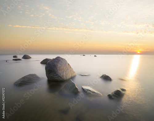 sea landscape  boulders in the water sunset and colorful sky  slow shutter speed