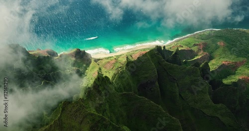 Aerial view flying over jungle mountain peaks revealing tropical coastline, Na Pali coast Kauai photo